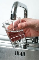 Wasserglas in das aus dem Wasserhahn Wasser eingefüllt wird